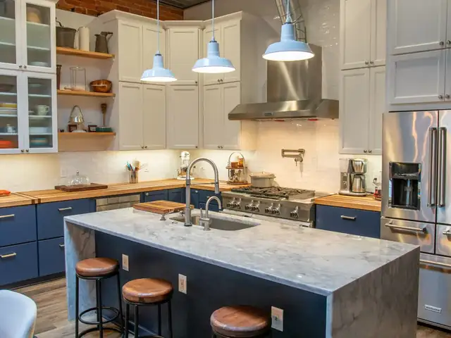 Goshen area kitchen with navy lower cabinets, white upper cabinets, butcher block counters and a marble-look waterfall island